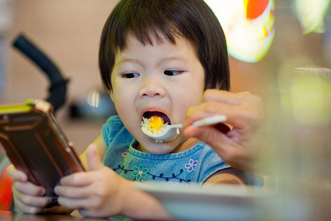 Cha mẹ nên tránh cho trẻ dùng điện thoại trong lúc ăn.